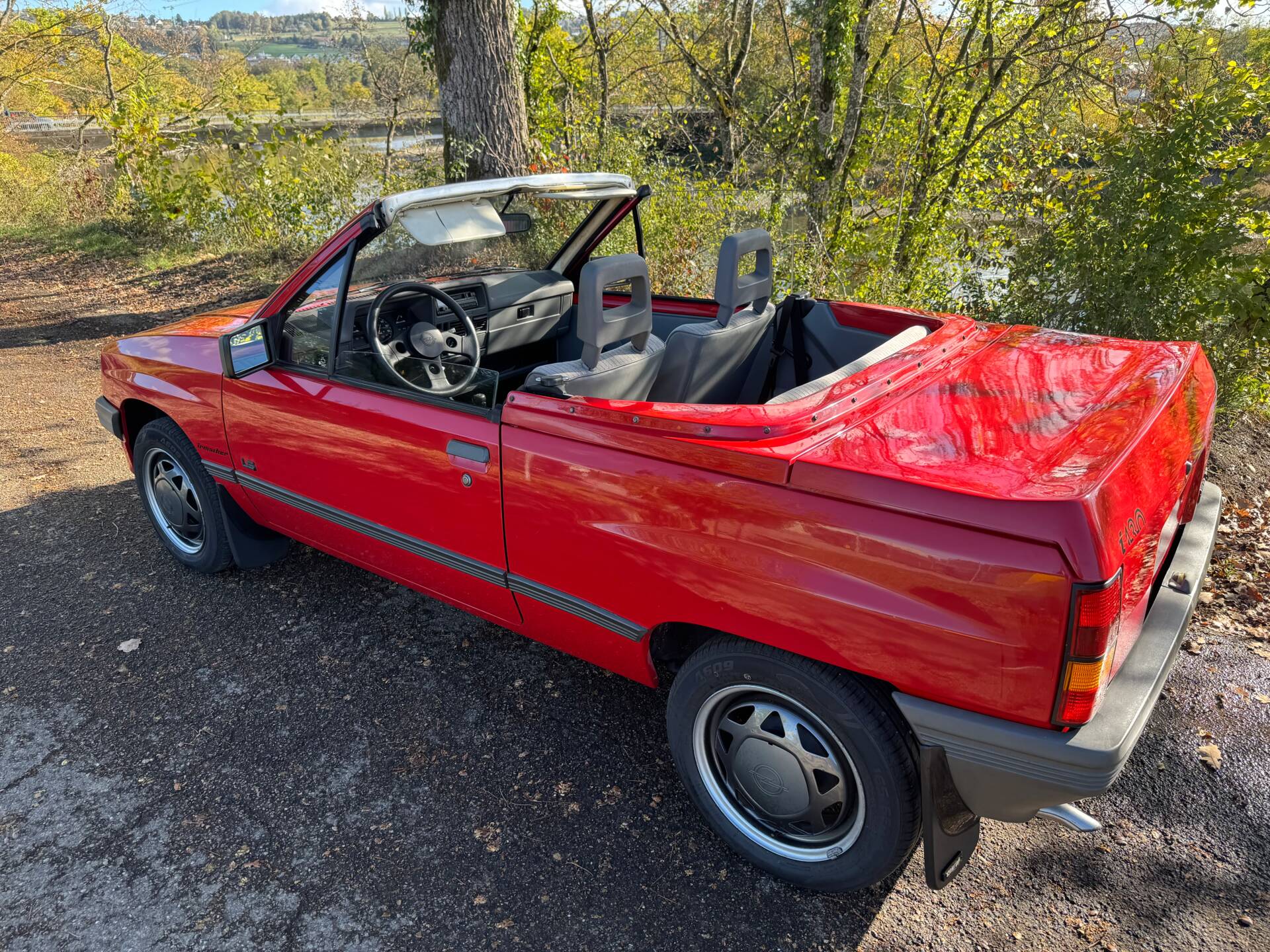Roter Opel Corsa A Spyder Irmscher mit offenem Verdeck, Heckansicht schräg von hinten am Flussufer
